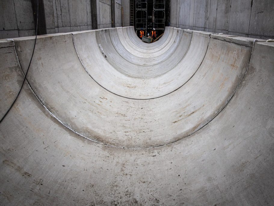 Blick in einen großen, runden Betontunnel mit Arbeiter im Hintergrund.