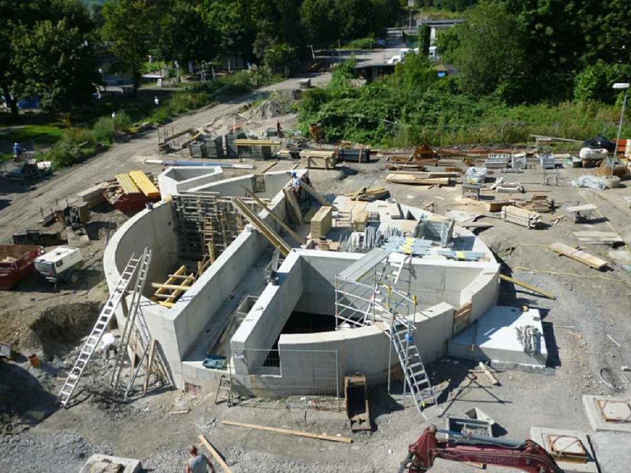 Baustelle mit Fortschritt im Bau, mehrere Materialien und Maschinen sichtbar.