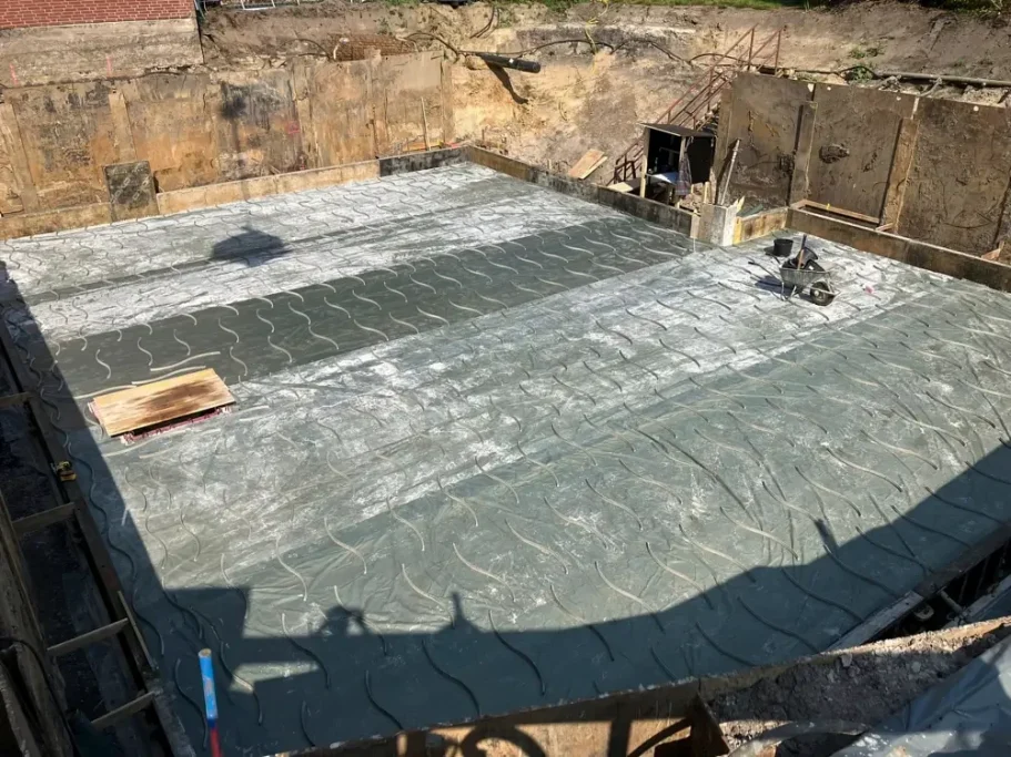 Bodenplatte einer Baugrube, fertig zum Gießen von Beton, mit Baustellenutensilien.