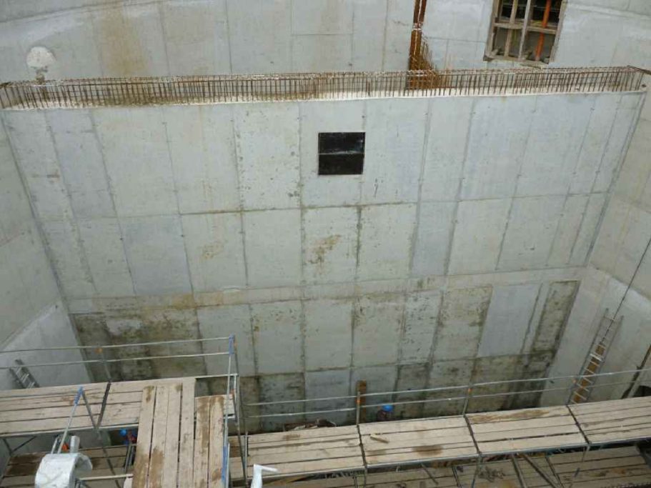 Baustelle mit unvollendeter Wand und Gerüst im inneren Bereich.