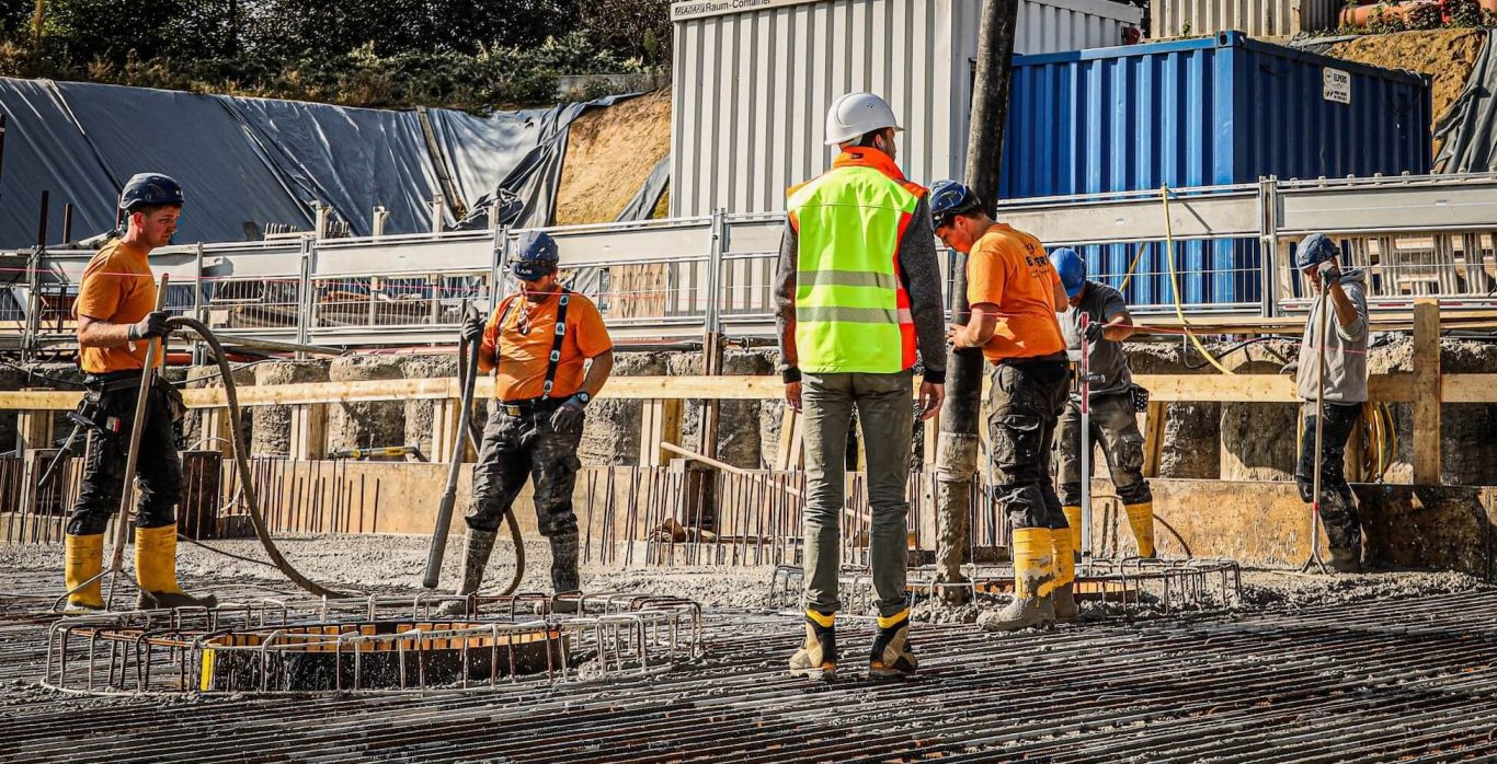 Bauarbeiter gießen Beton auf einer Baustelle.