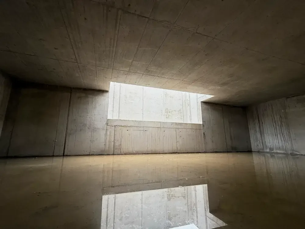 Leerer, moderner Raum mit Betonwänden und einem schmalen Fenster, das Licht hereinlässt.