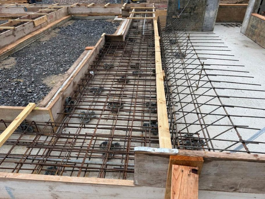 Frisch gegossener Betonboden mit Baugeräten im Hintergrund.